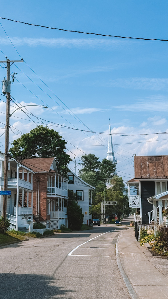 Rue calme de La Malbaie avec une église en arrière-plan, architecture typique québécoise