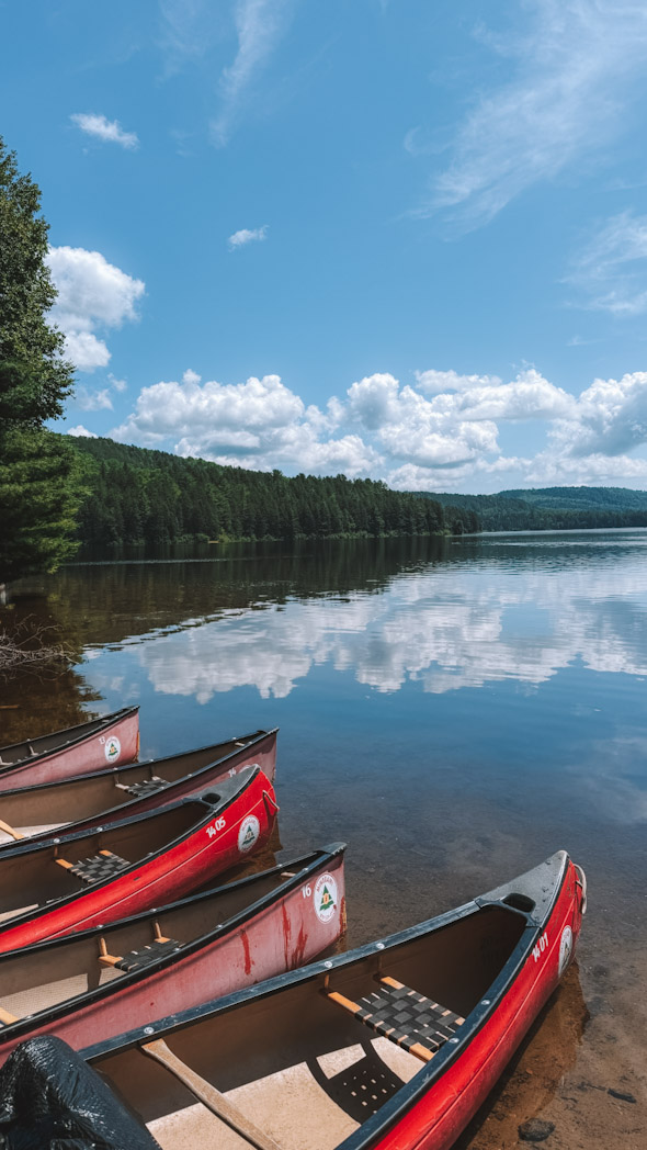 Canoë sur un lac paisible entouré de forêt dans le Parc national de la Mauricie