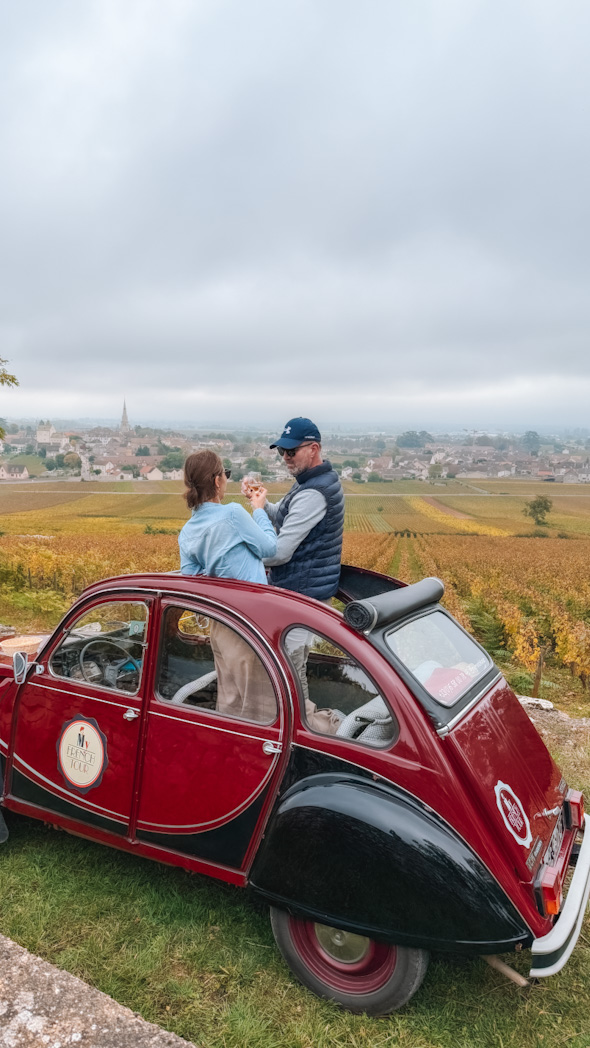 Couple profitant d’une balade romantique en 2CV parmi les vignobles sur la Route des Grands Crus de Bourgogne